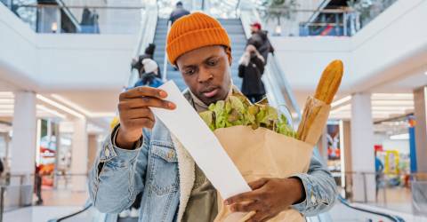 Een man heeft een zak met boodschappen vast en schrikt van de prijs