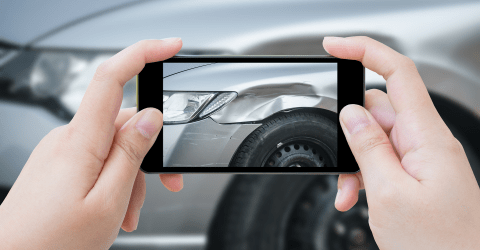 Een vrouw maakt een foto van de schade aan haar auto